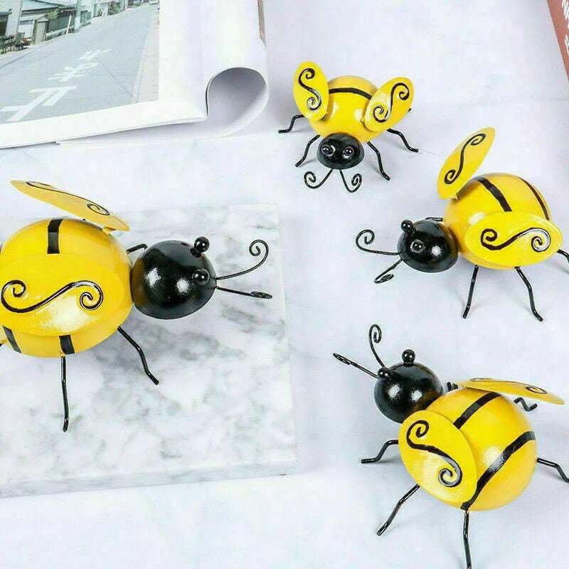 Four decorative metal bumble bee sculptures in a natural garden setting
