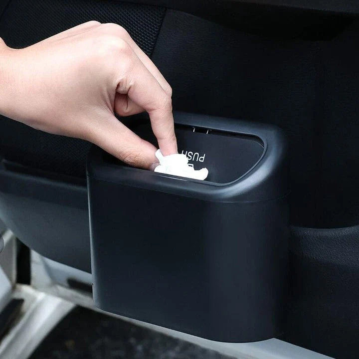 A compact black car bin with a press-type lid, designed to hang on the door panel and store garbage securely