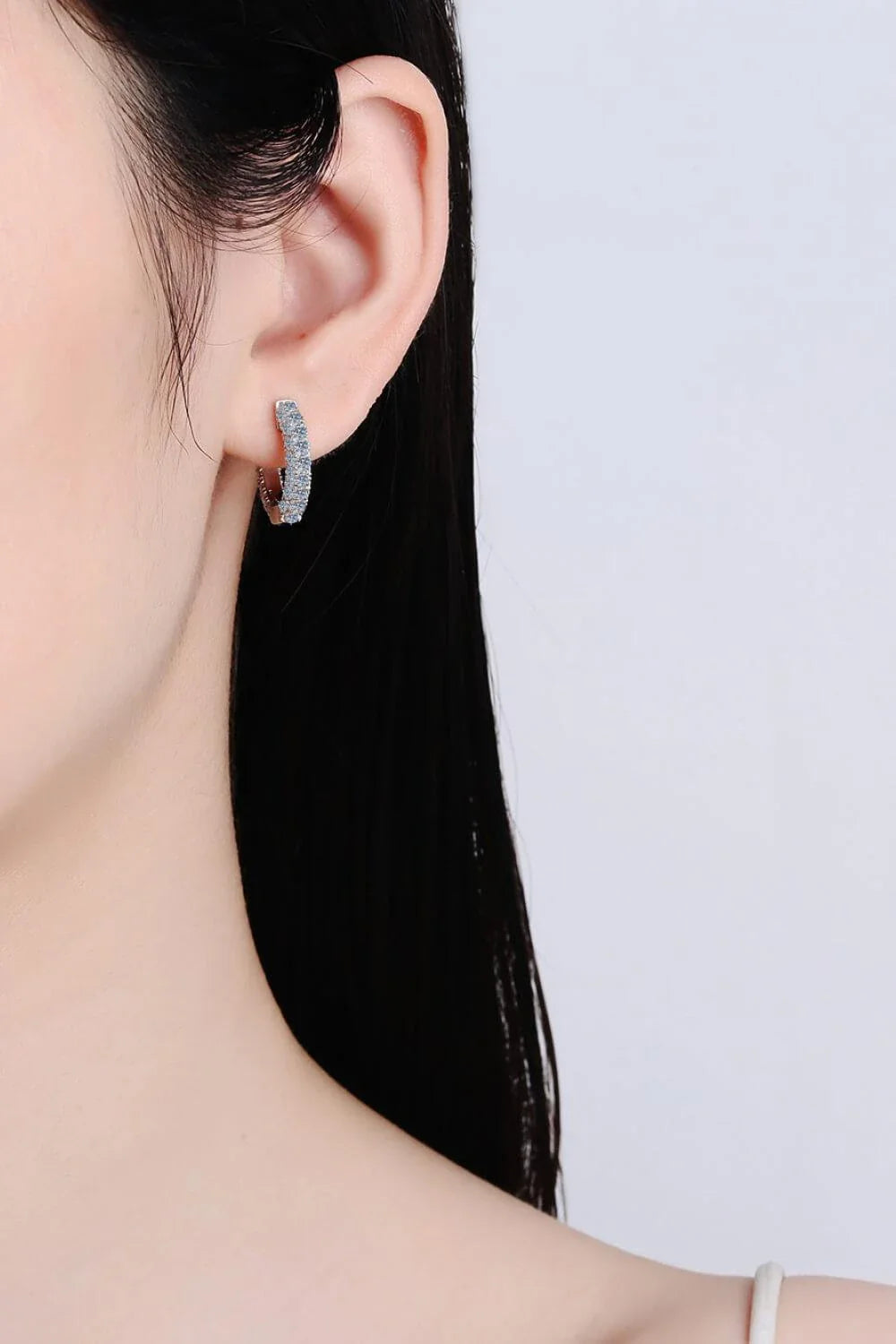 Pair of elegant sterling silver huggie earrings adorned with dazzling moissanite stones, showcasing a minimalist and sophisticated design.