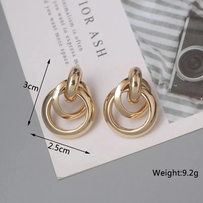 Elegant geometric statement earrings with a luxurious gold finish, featuring a unique hollow twist design.
