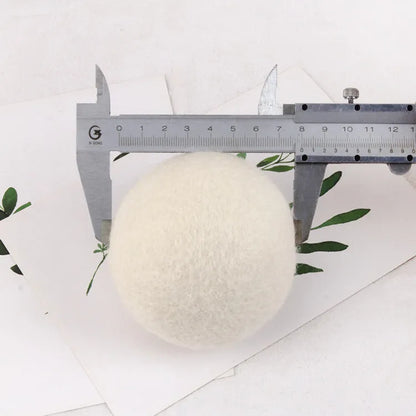 A 100% wool drying ball for laundry next to a plain cotton storage bag on a background.
