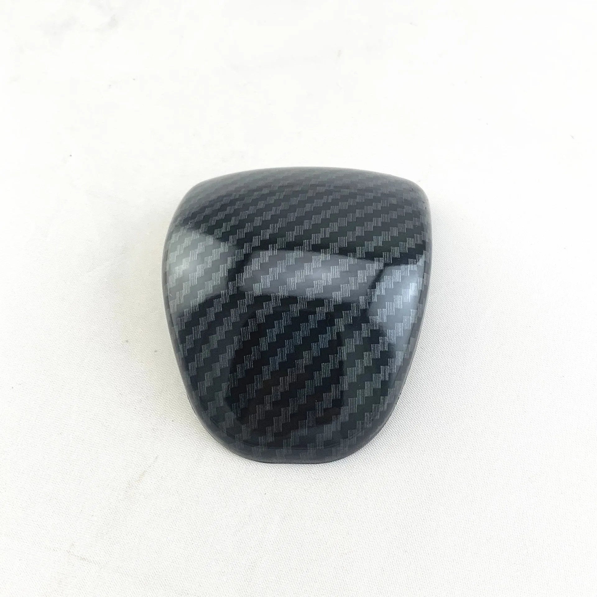 Black carbon fibre effect plastic cover for a car gear shift knob.