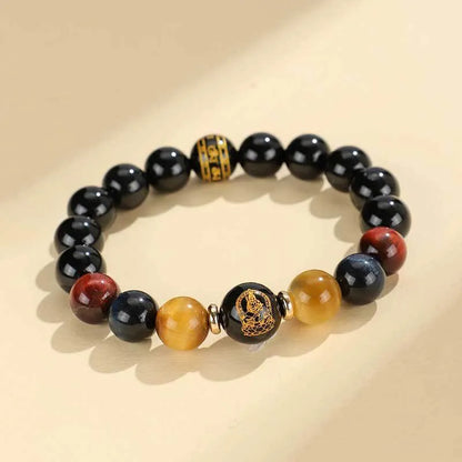 Handcrafted black agate and tiger eye stone beaded bracelet with a central carved zodiac deity charm.