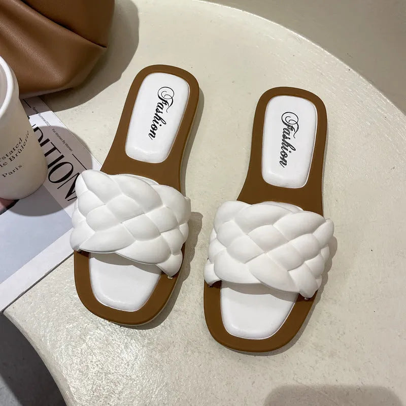 Women's white PVC beach sandals with a thick, patterned sole on a sandy background.