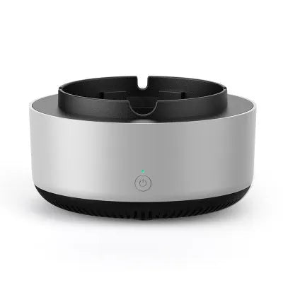 Grey intelligent electronic air purifier ashtray with fan, shown on a desk next to a cigarette.