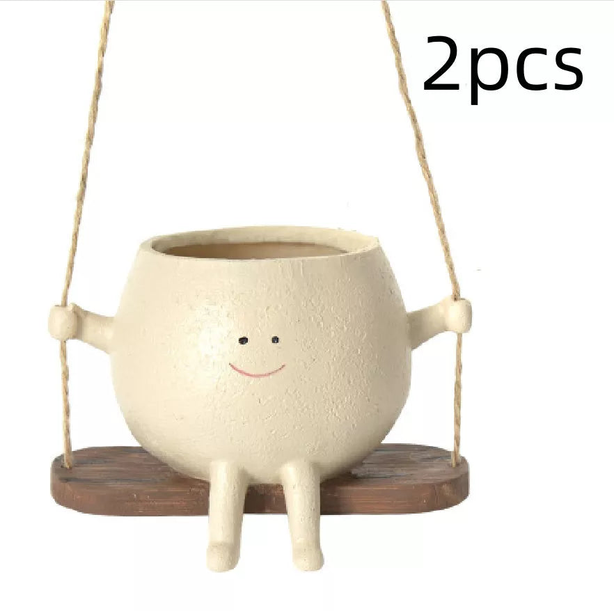 Swing face hanging flower pot with child's smiling design, made of durable resin