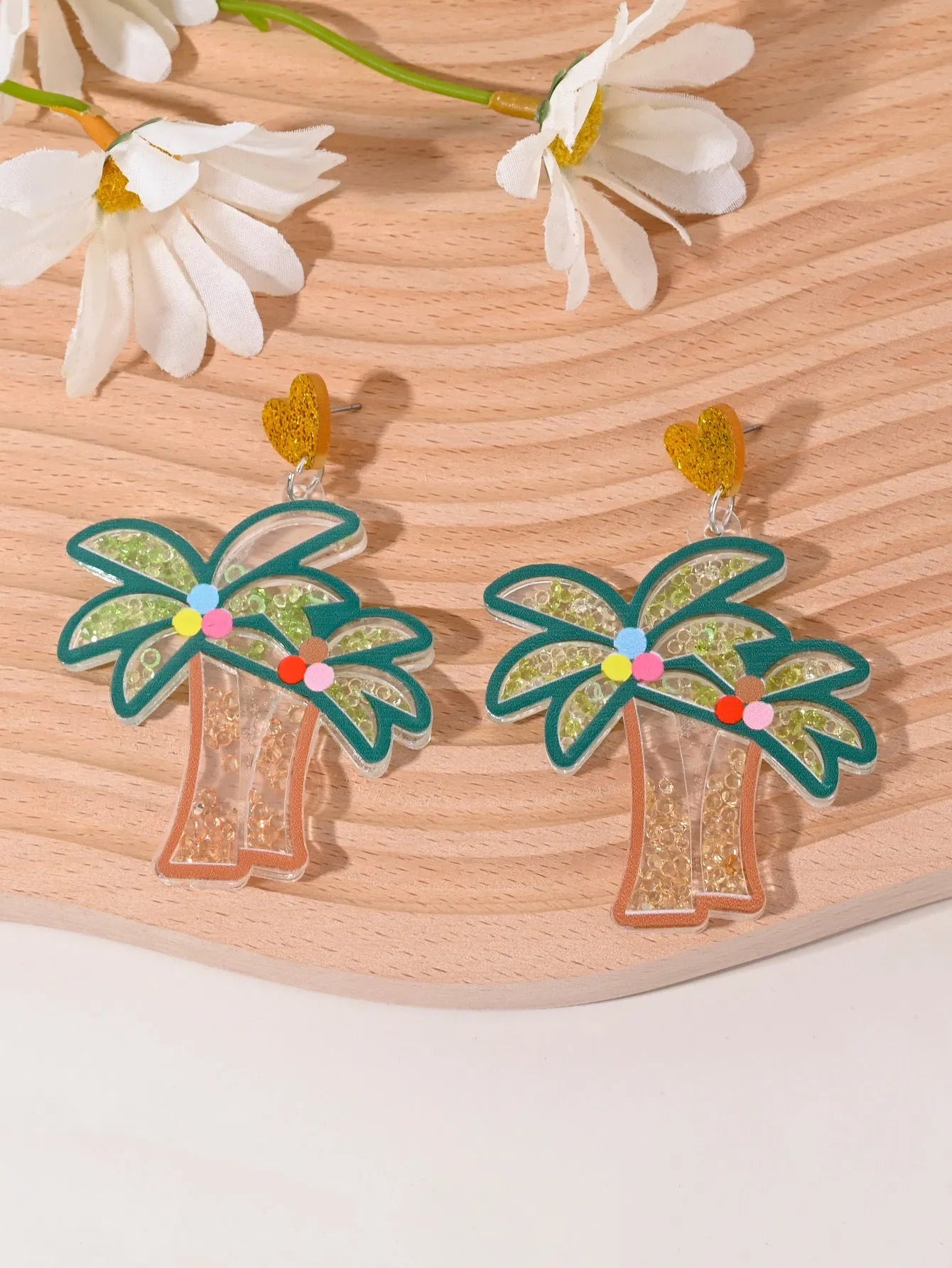 A pair of colourful acrylic earrings shaped like a strawberry and a cherry on a woman's ear.