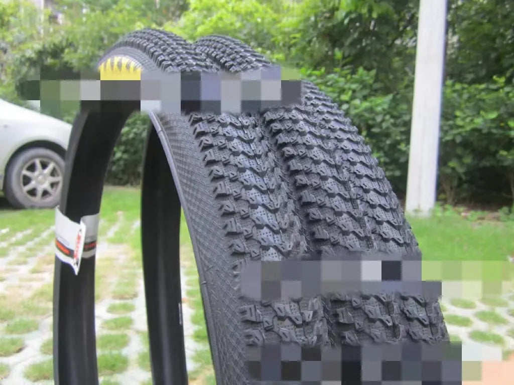 Mountain bike tyre with black tread and sidewall, showing size options like 26x1.95 and 29x2.1 inches for off-road cycling.