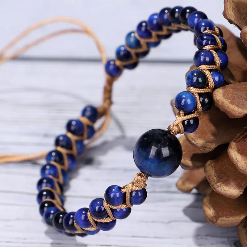 Close-up of a hand-woven geometric bracelet with a blue Tigereye stone on a wrist.
