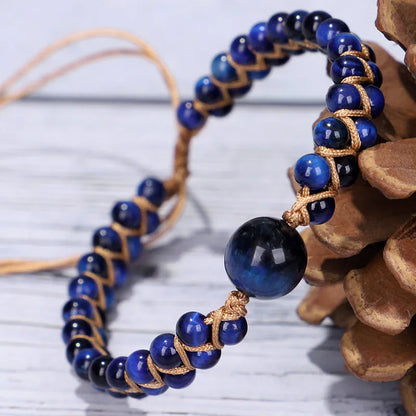 Close-up of a hand-woven geometric bracelet with a blue Tigereye stone on a wrist.