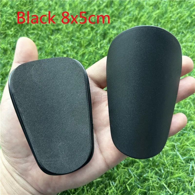 Extra small 8x5cm black and white plastic football shin guards for junior players.