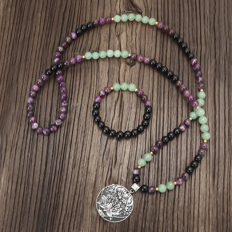 Long stone bead necklace with alloy lotus pendant and matching bracelet set on a background.