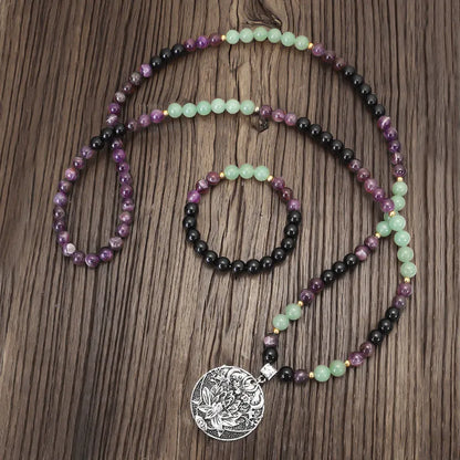 Long stone bead necklace with alloy lotus pendant and matching bracelet set on a background.