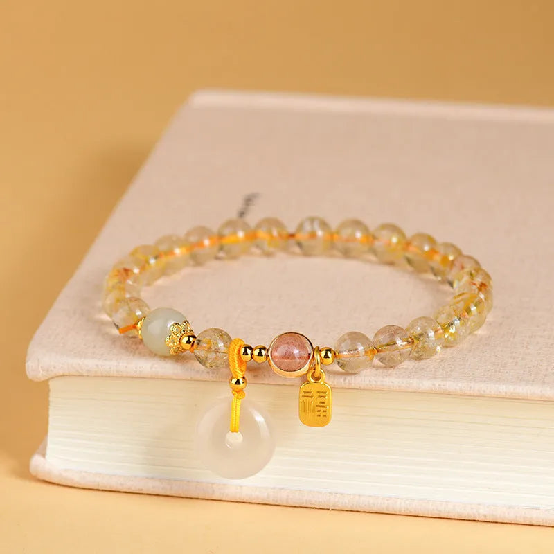 Gold rutilated quartz crystal bracelet with geometric peace buckle pendant and safety clasp