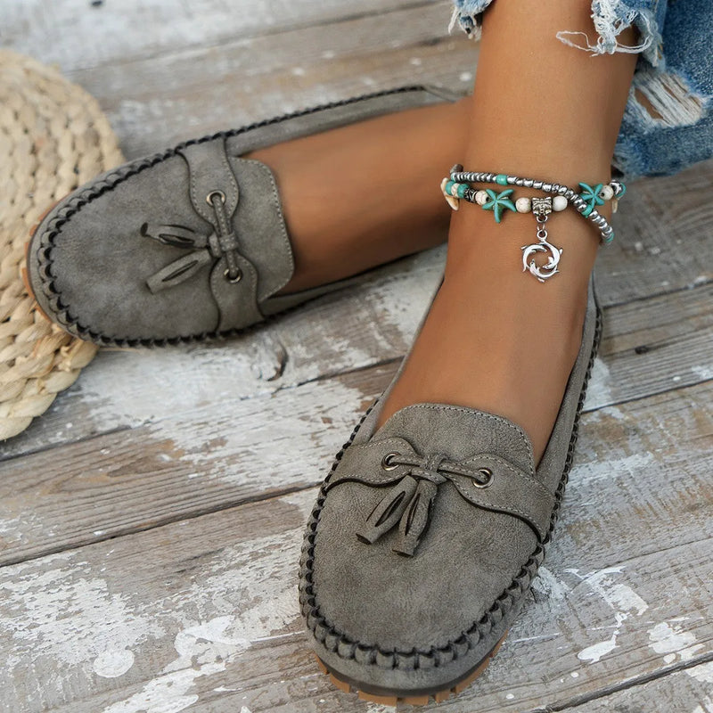 Women's casual flat shoes with bow detailing in pure suede, available in apricot, blue, gray, and pink, featuring a low-cut upper with a shallow opening, a round toe, and an injection-moulded polyurethane sole for everyday wear.