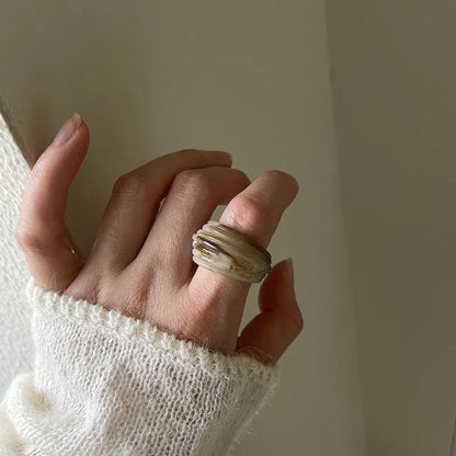 Geometric Chinese-style wide resin ring in brown and white colours on a plain background.