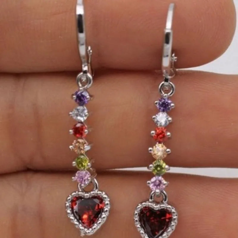 A pair of small gold-coloured heart-shaped alloy earrings on a plain background.