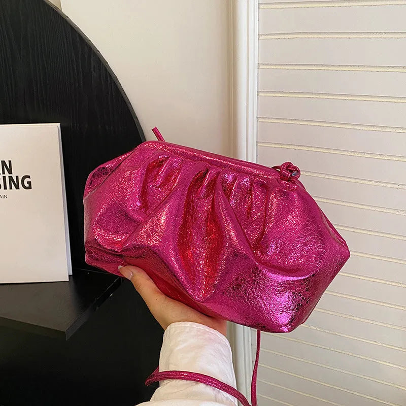 Rose red crossbody bag with hair clip strap clasp on a table, showing shell shape and front zipper.