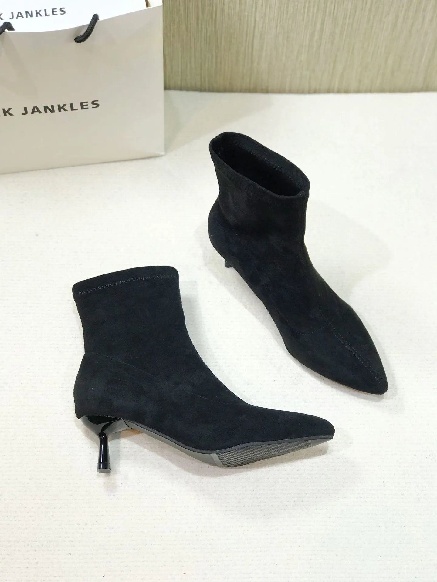 Women's black pointed toe ankle boots with a stiletto heel on a neutral background