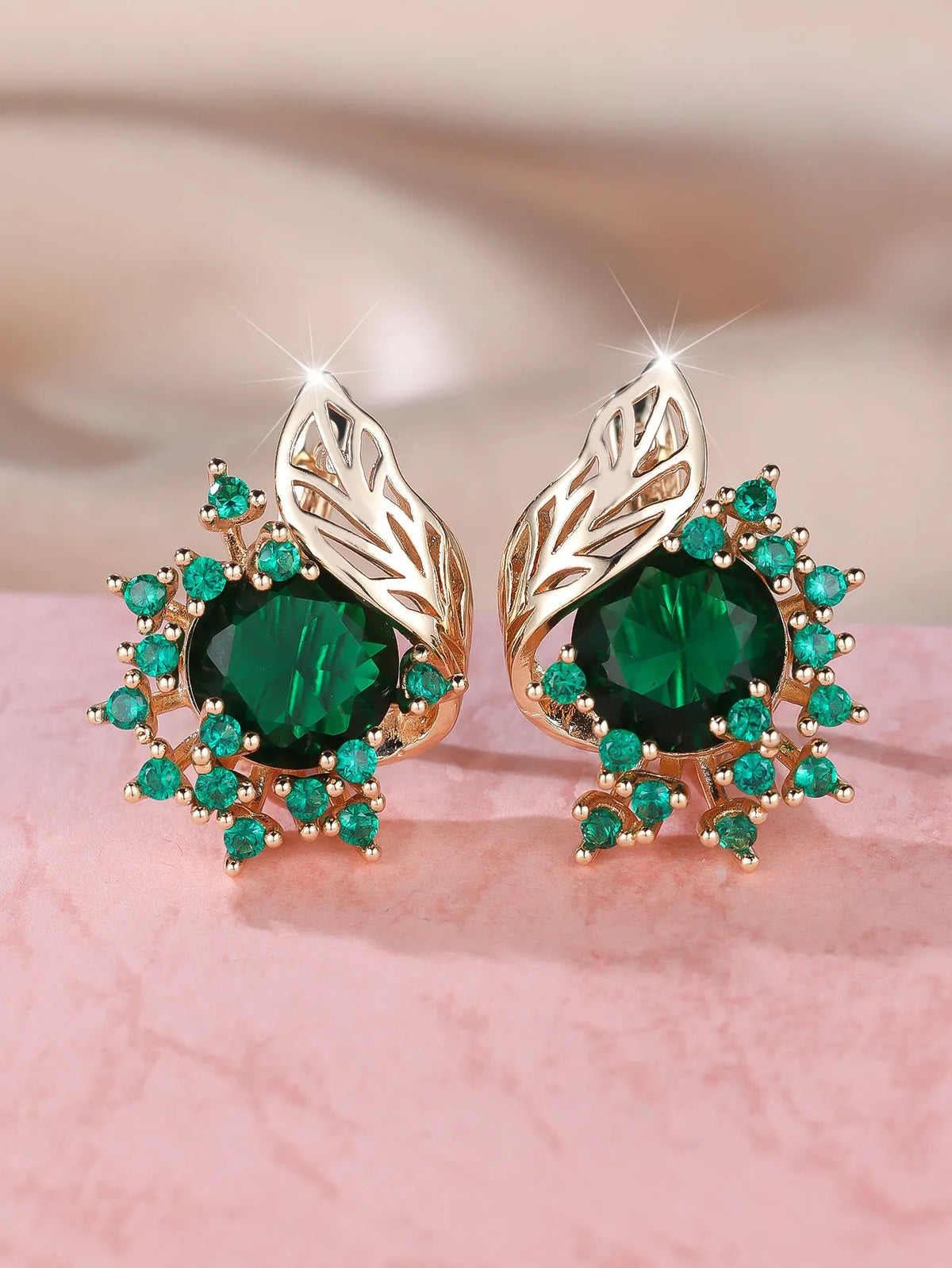 Rose gold plated women's stud earrings with a round flower shape, feather detail, and a central cubic zirconia stone.