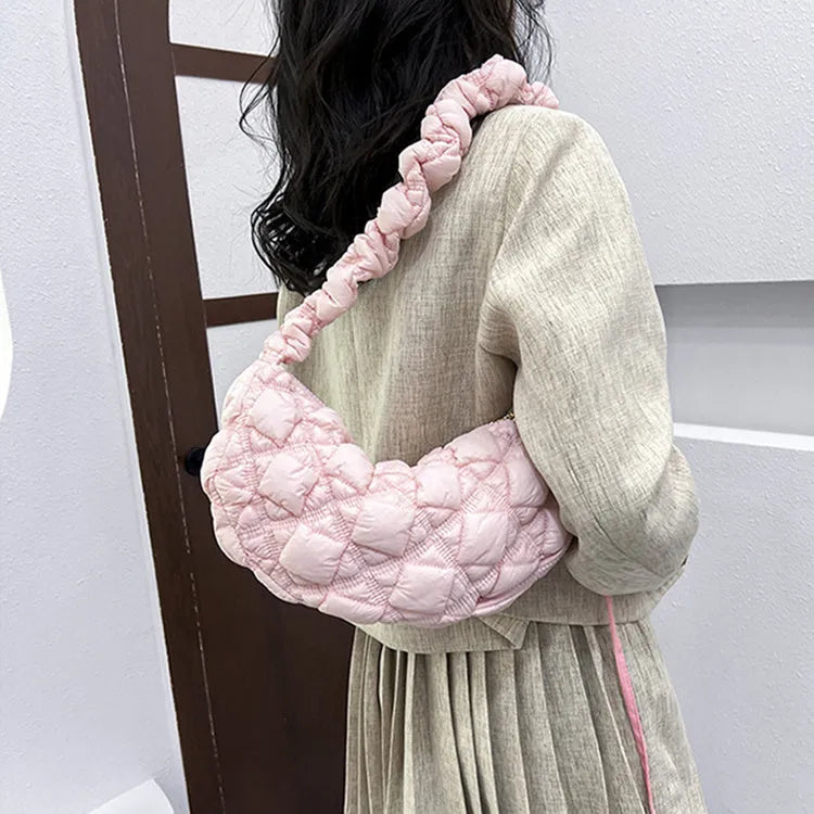 Women's light grey nylon underarm messenger bag with adjustable long strap, shown worn crossbody.