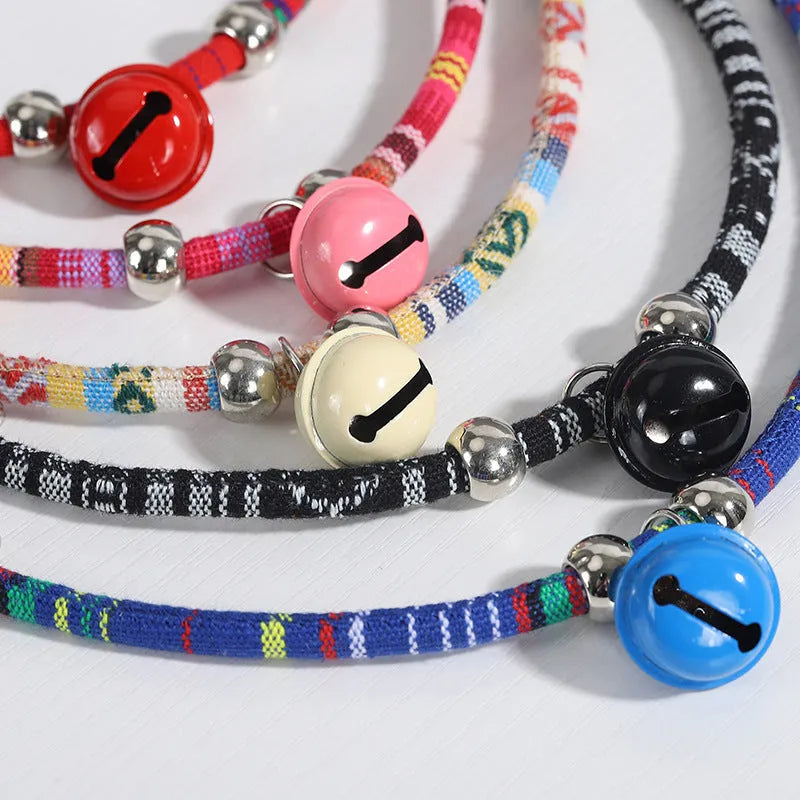 Coloured ethnic pattern adjustable dog collar with metal bell and reflective strip on a nylon strap.