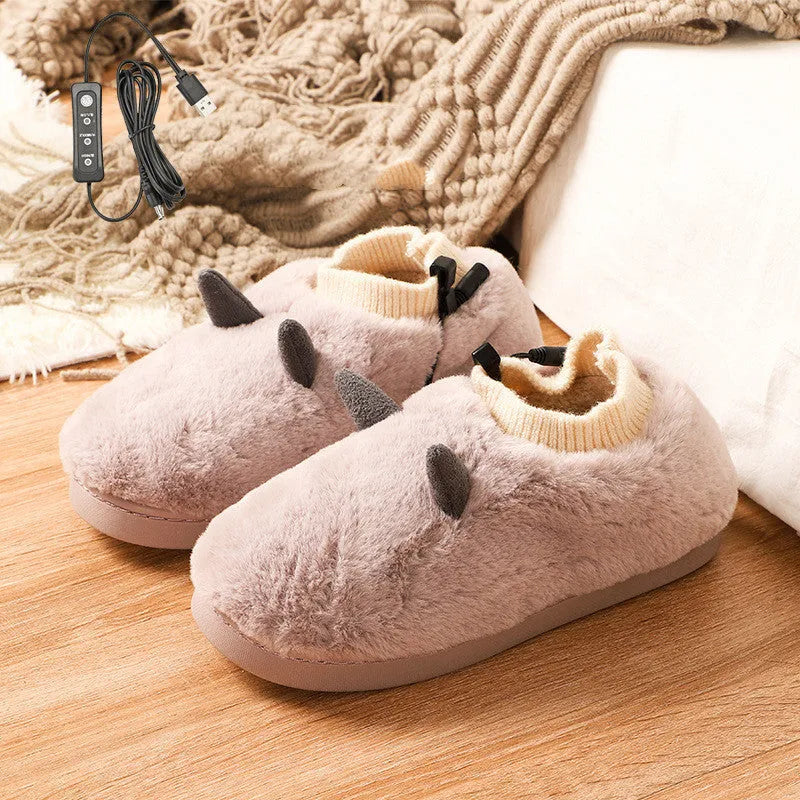 USB heating slippers in black plugged into a laptop, showing the cable and soft velvet upper.