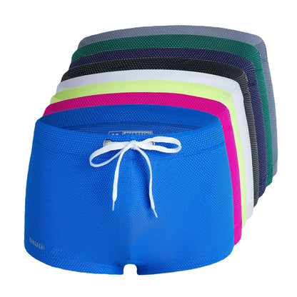 Men's low waist swim trunks in stretch nylon on a man, showing elastic waistband and boxer-style cut.