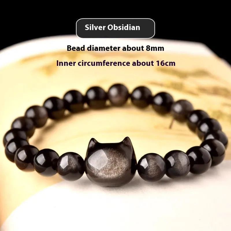 Obsidian cat head bracelet with round stone beads and a gold-toned cat charm on a wrist.