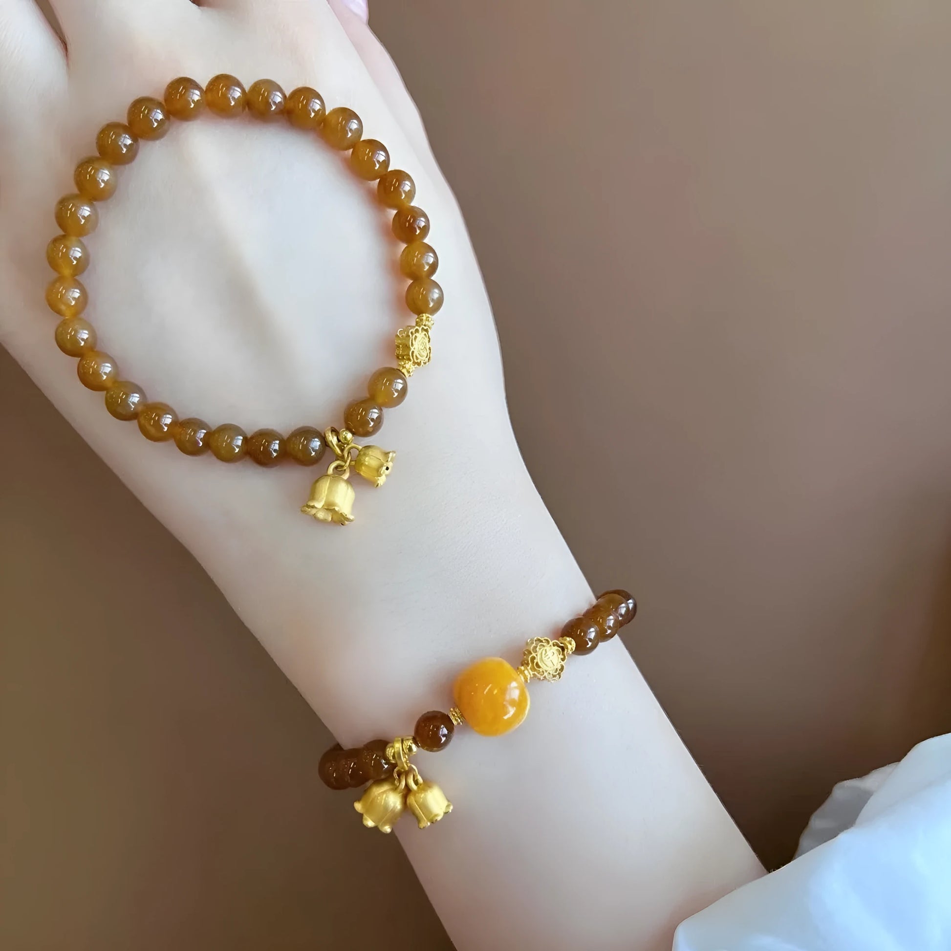 Caramel-coloured women's bracelet with beeswax Lily, music note, and blessing charms in New Chinese style.