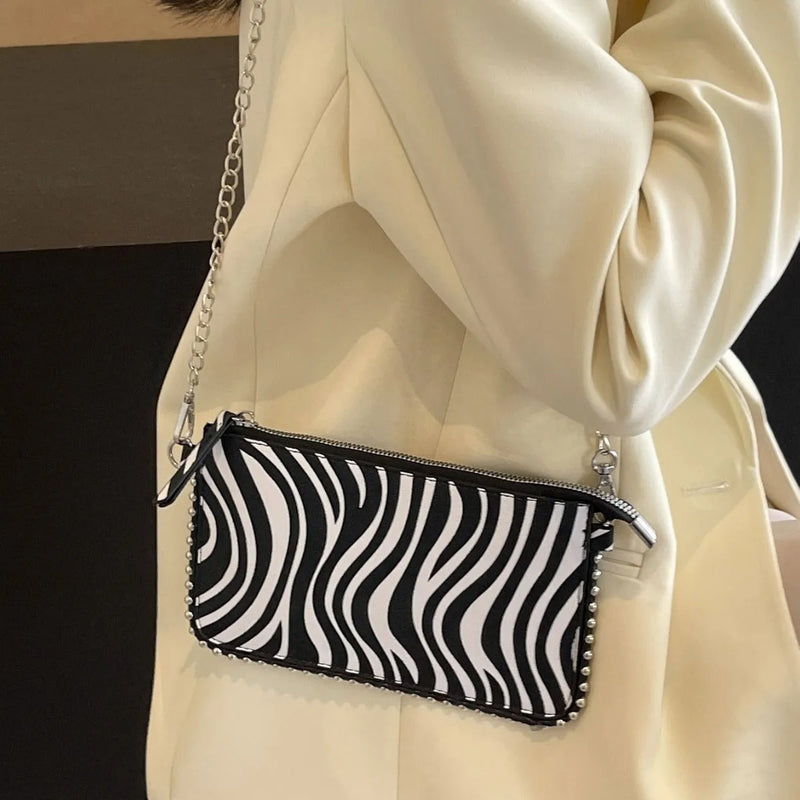 Western style women's crossbody bag with chain strap detail and horizontal square silhouette, featuring a medium-soft PU construction and dark brown, brown, or white colour options for casual underarm carry.