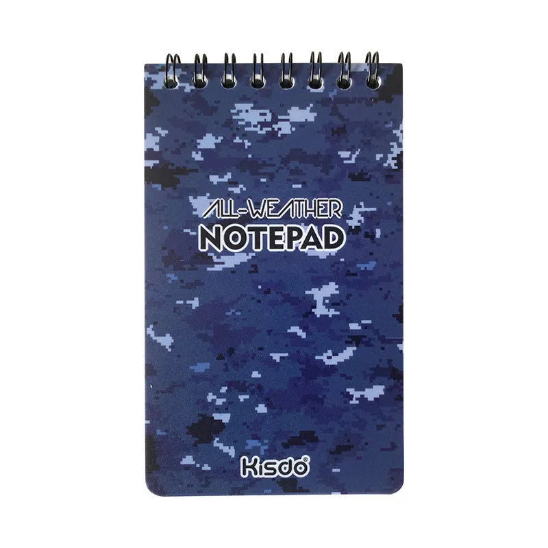 Spiral-bound waterproof notepad in camouflage colour, open on a wooden surface with a pen.