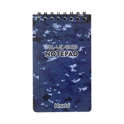 Spiral-bound waterproof notepad in camouflage colour, open on a wooden surface with a pen.