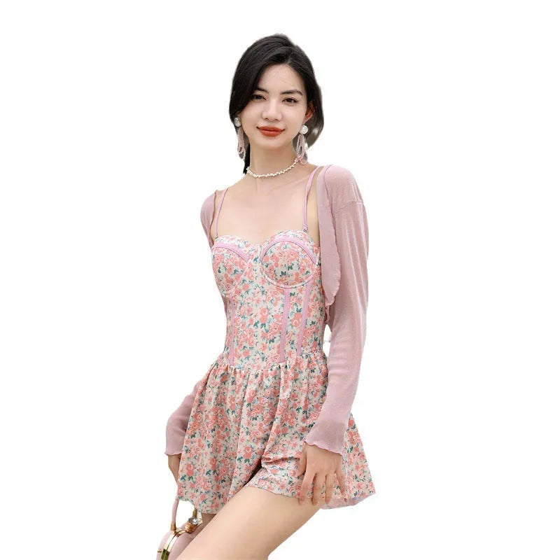 Women's pink floral one-piece jumpsuit swimsuit with suspender straps on a hanger.