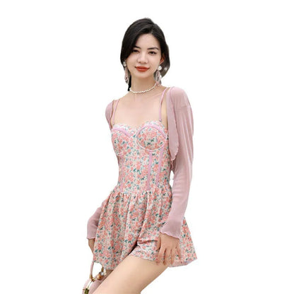 Women's pink floral one-piece jumpsuit swimsuit with suspender straps on a hanger.