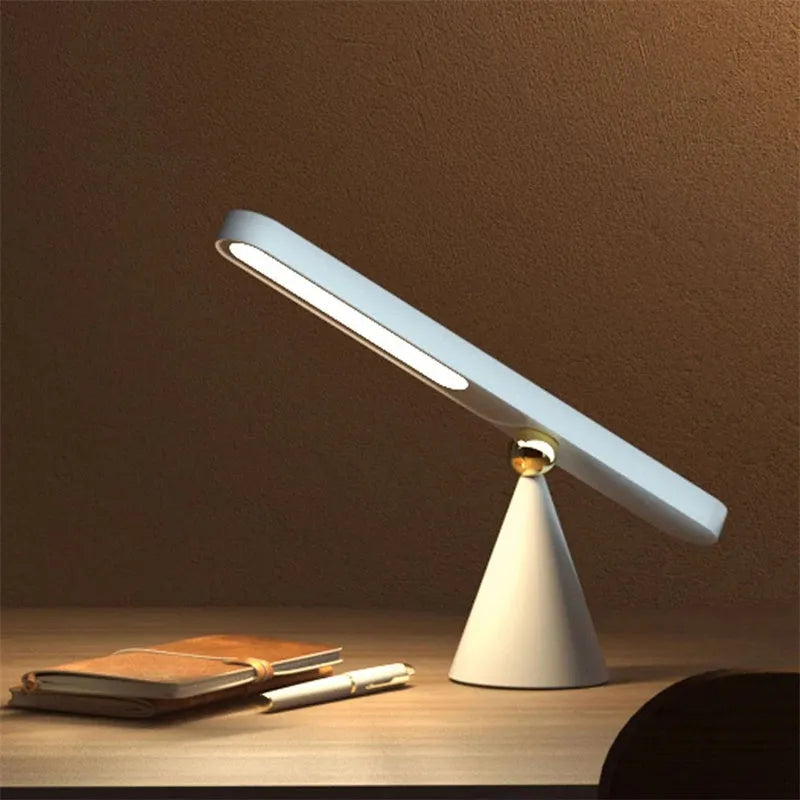 White geometric desk lamp with magnetic base and touch control on a wooden table.