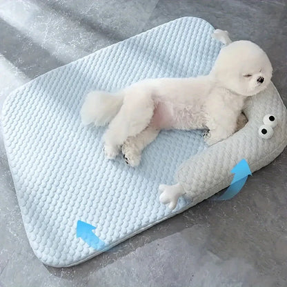 Blue pet bed cushion with big-eyed monster design, shown on a wooden floor.