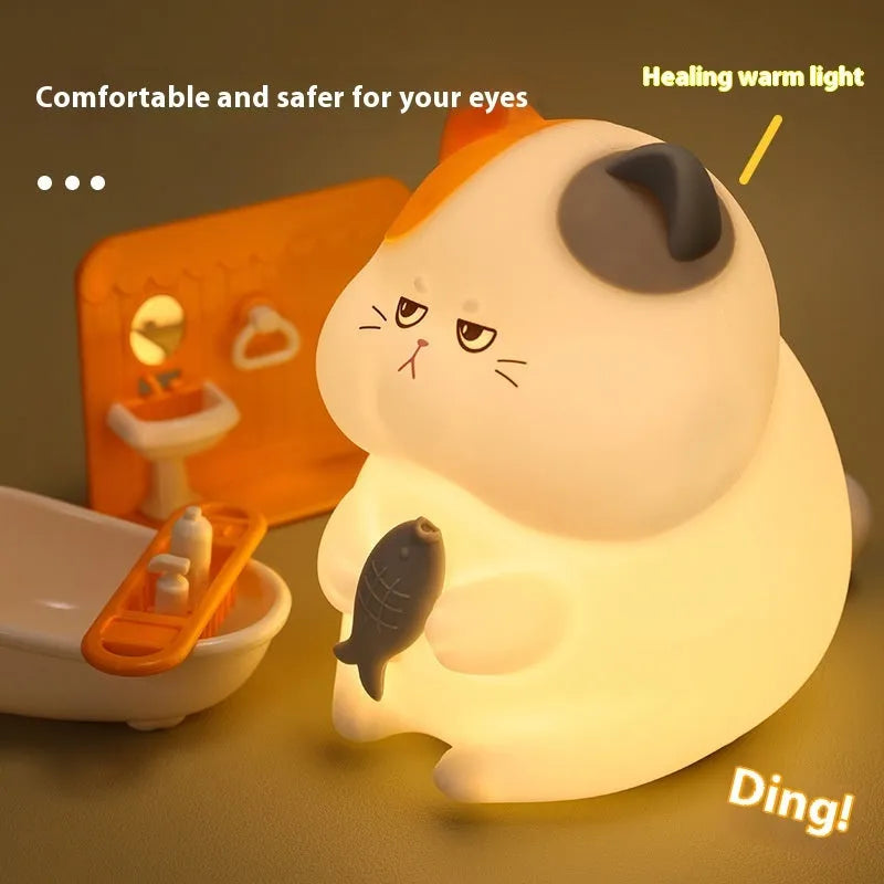 Yellow cartoon Greedy Cat desktop night light with plug, shown on a wooden desk.