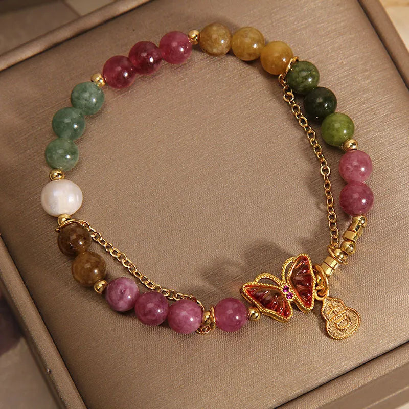 Close-up of a jade green tourmaline butterfly gourd charm on a brown agate bracelet for women.