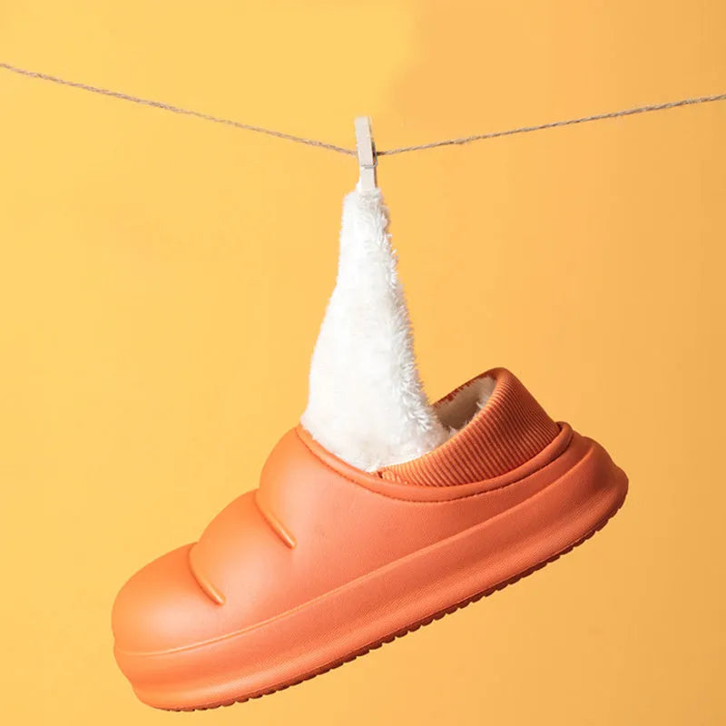 Pair of yellow waterproof EVA slippers with plush lining and a textured non-slip sole on a wooden floor.