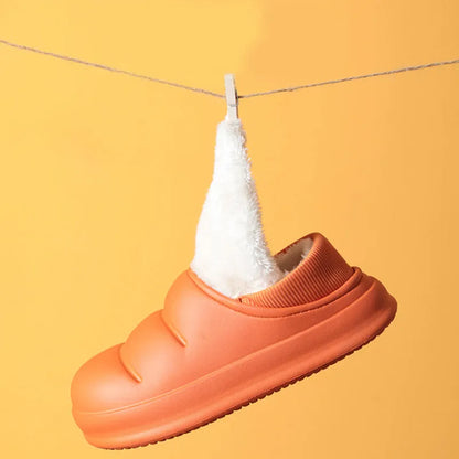 Pair of yellow waterproof EVA slippers with plush lining and a textured non-slip sole on a wooden floor.