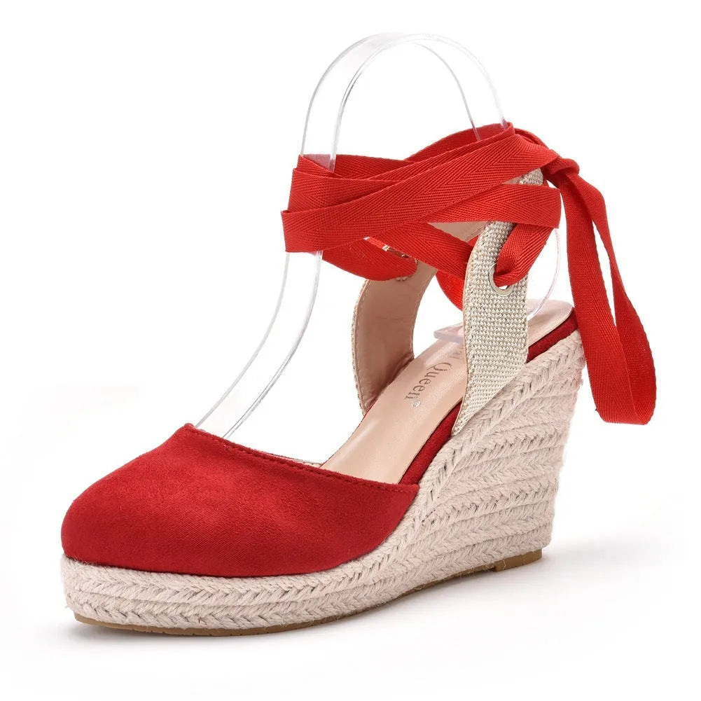 Women's red bohemian sandals with wedge heel, beaded strap, and adjustable ankle buckle on a wooden surface.