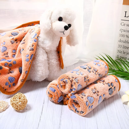 Coral fleece dog blanket with paw print pattern, shown in beige colour, laid flat to show size and soft texture.