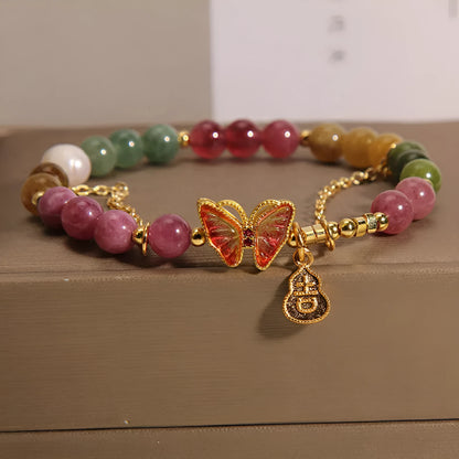 Close-up of a jade green tourmaline butterfly gourd charm on a brown agate bracelet for women.