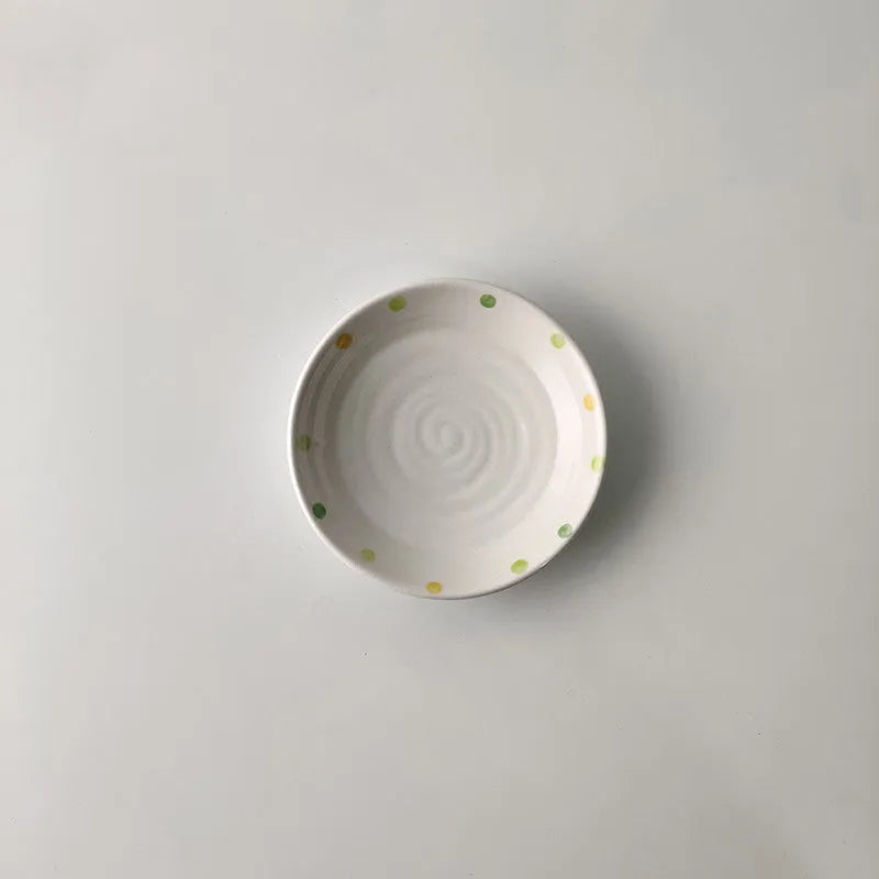 Japanese-style dot pattern porcelain plates and bowls in irregular oval and round shapes on a table.