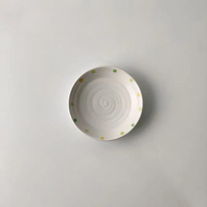 Japanese-style dot pattern porcelain plates and bowls in irregular oval and round shapes on a table.