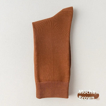Pair of solid-colour men's mid-calf socks made from combed cotton on a wooden background