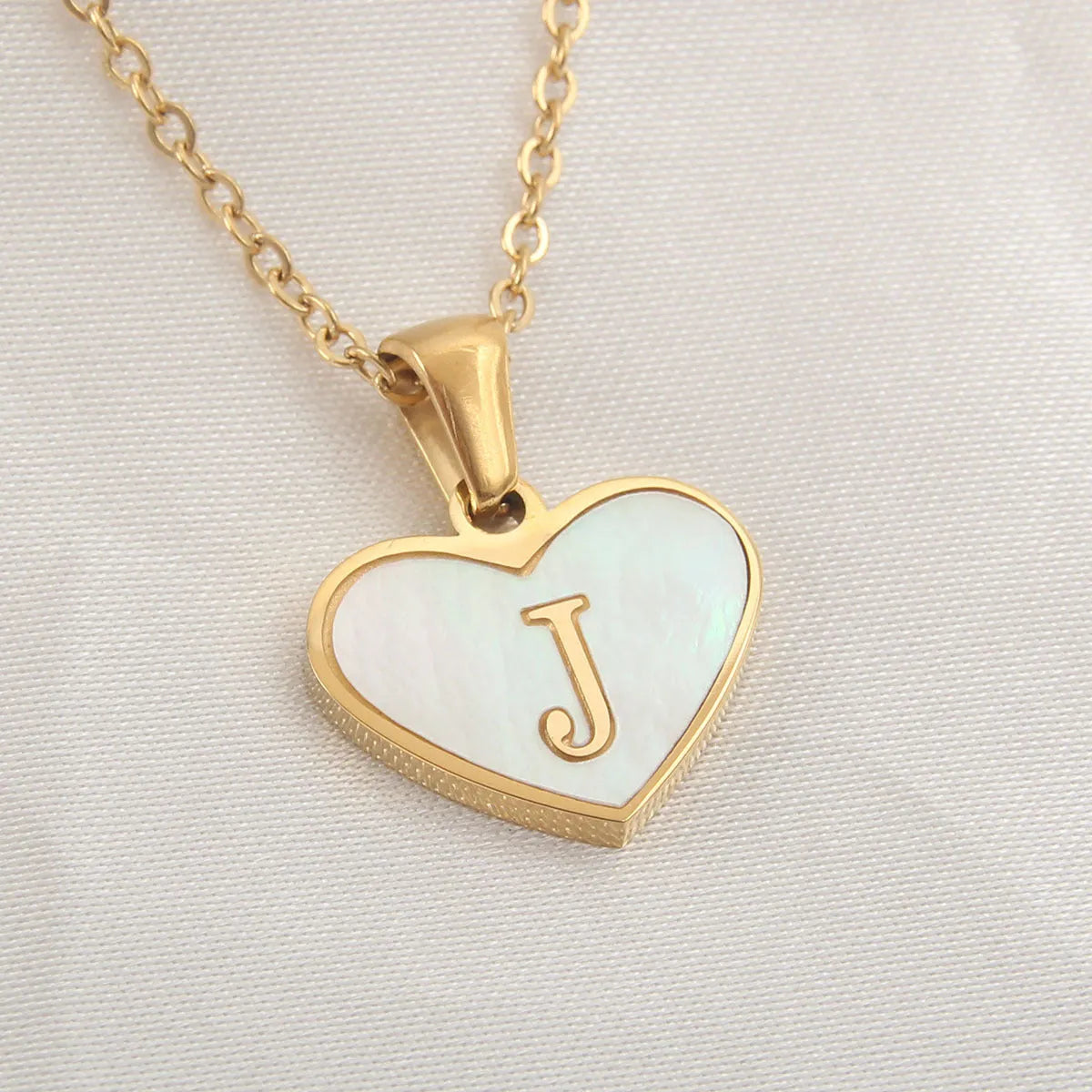 Gold-plated heart necklace with white shell pendant showing letter personalisation option
