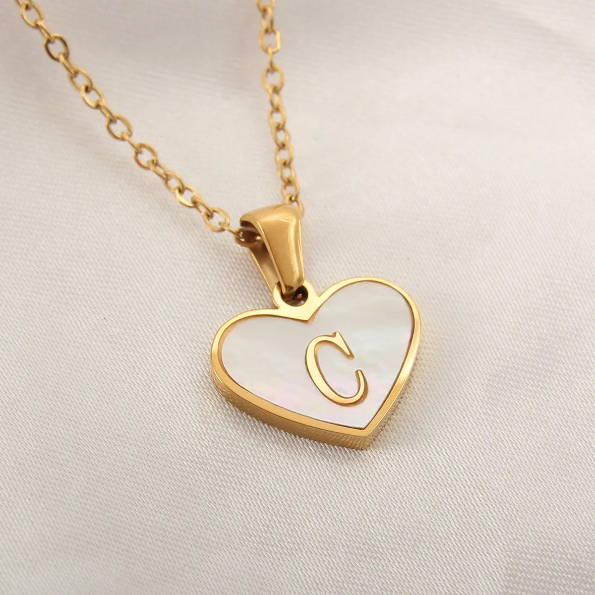 Gold-plated heart necklace with white shell pendant showing letter personalisation option
