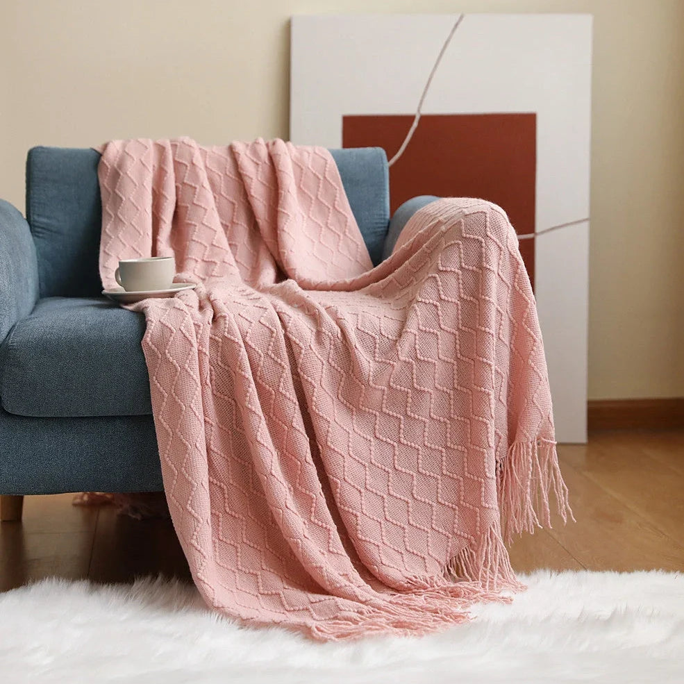 Nordic knitted blanket in beige colour showing open knit pattern on grey sofa